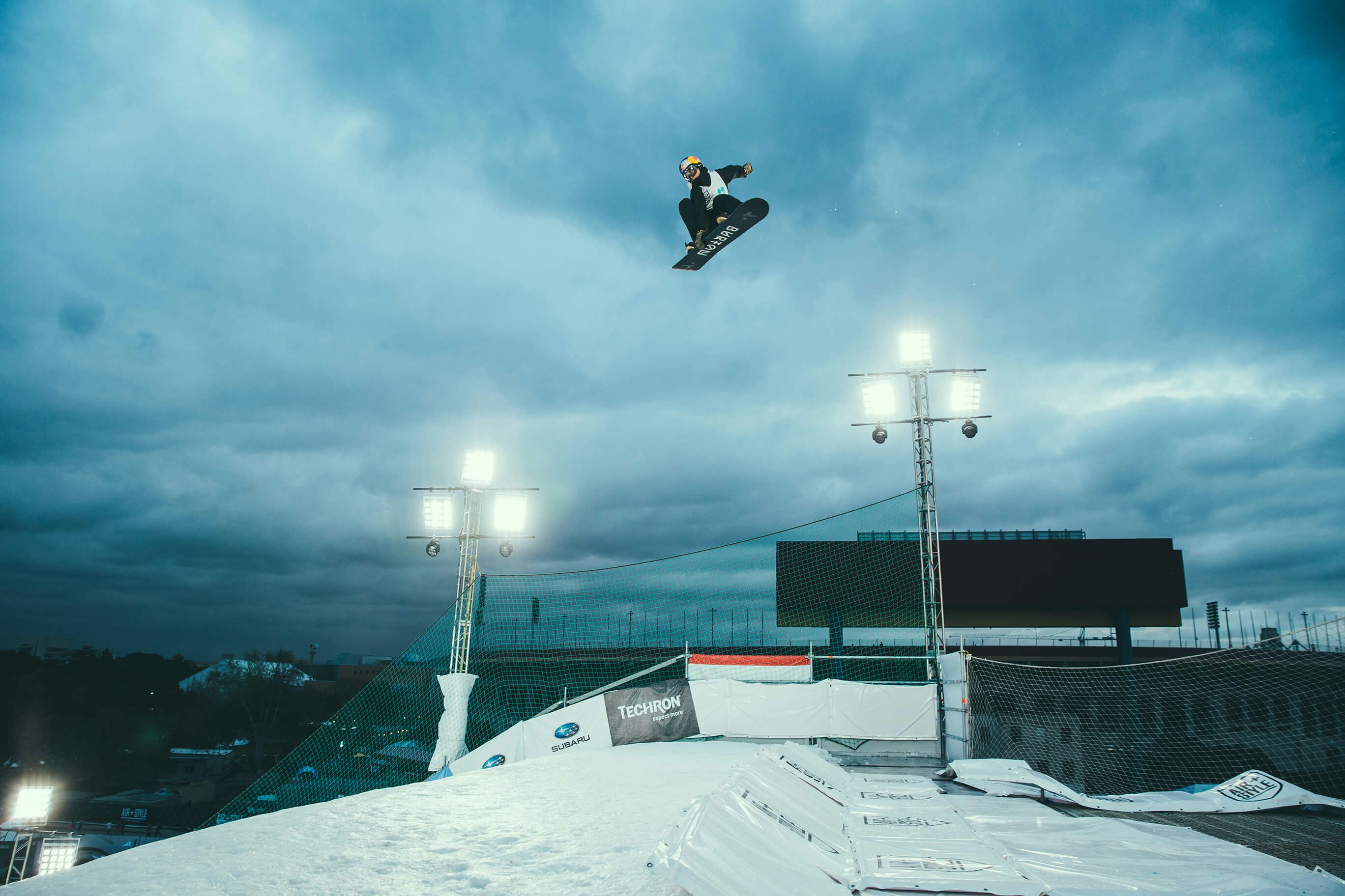 person snowboarding in mid air under cloudy sky